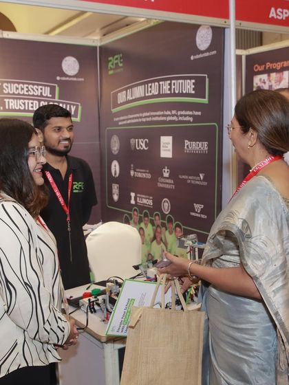 Our team engages with an educator at our expo booth, discussing how our programs help students get into top global universities.
