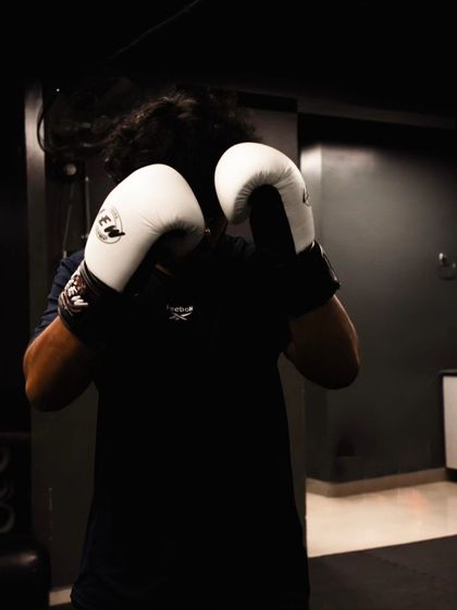 A fighter stands ready in a classic boxing stance, gloves up, chin down, prepared to throw or defend.