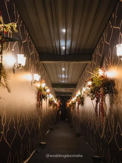 Even walkways should feel like part of the celebration. We designed this corridor with bold patterned walls, soft floral arrangements, and warm sconce lighting to create a luxurious and intentional transition space for guests.
