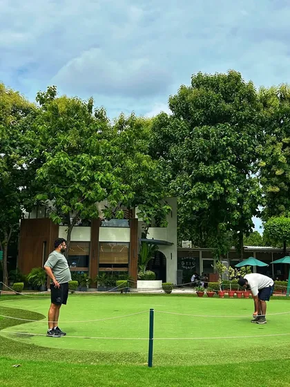 Two golfers chat on the putting green, with our beautiful clubhouse and cafe in the background.