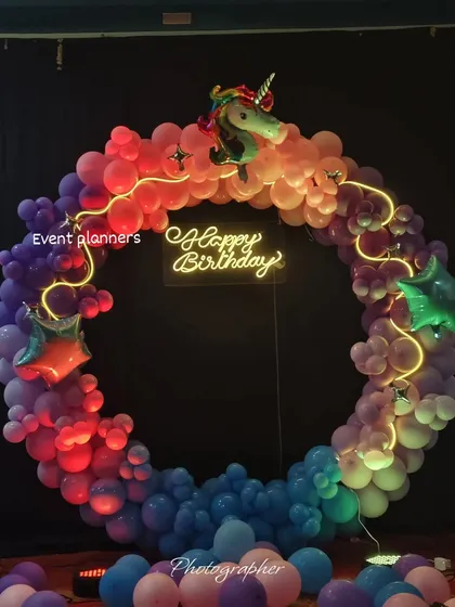 A close-up of the unicorn balloon ring with a "Happy Birthday" neon sign.