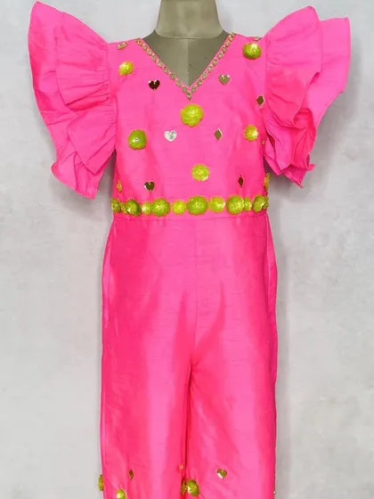 A fun and fluorescent pink jumpsuit with bright green accents. The ruffled sleeves and embellished neckline make this a perfect outfit for a mehendi party.