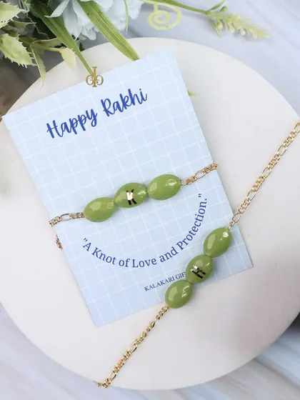 A personalized Quartz Rakhi in a lovely olive green, presented on a "Happy Rakhi" card that reads "A Knot of Love and Protection."