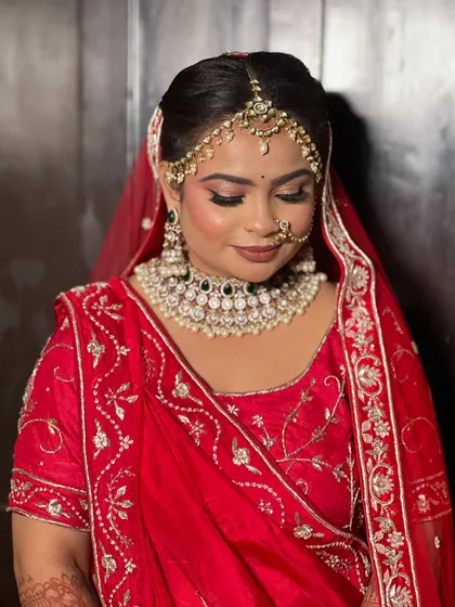 A beautiful bride in red, her makeup featuring soft brown tones on the eyes and a matte lip.