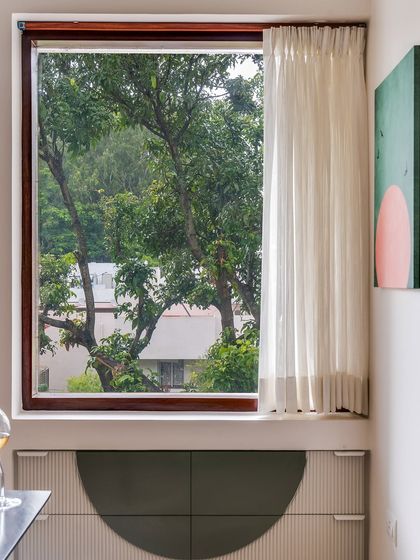 A detail shot of the dining area, showing the custom-designed sideboard with its unique semi-circle pattern, set against the large window with its serene view.