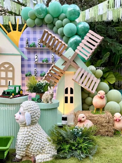 This setup includes a charming windmill, a fluffy sheep, and adorable chick props on hay bales.
