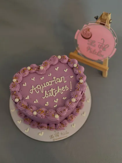 Another view of the custom heart-shaped bento cake. The purple buttercream is piped carefully around the edges and dotted with edible pearls to frame the handwritten message.