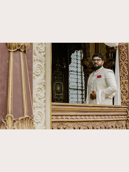 A handsome portrait of the groom framed by the intricate architecture of the venue.