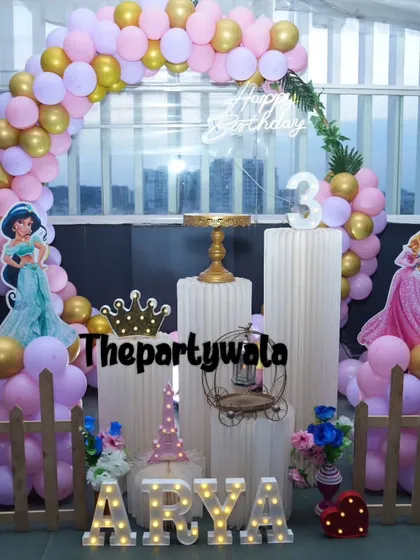 This outdoor princess setup for a 3rd birthday features a beautiful pink and gold balloon arch. The character cutouts and light-up name sign create a magical photo opportunity.