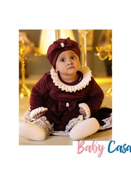 A vintage-inspired look for a precious little one. This deep maroon velvet dress with a lace collar and matching cap is a beautiful and timeless outfit for a baby's first winter celebration.