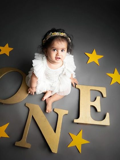A classic overhead shot celebrating the big "ONE". Using simple props like these letters and stars on a dark background really makes the moment pop.