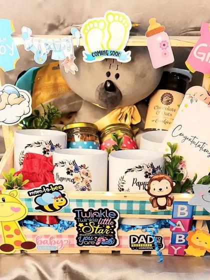 Another take on our popular baby shower hamper. This one is filled with treats, mugs for mom and dad, and a cute grey teddy bear, all decorated with fun baby-themed cutouts.
