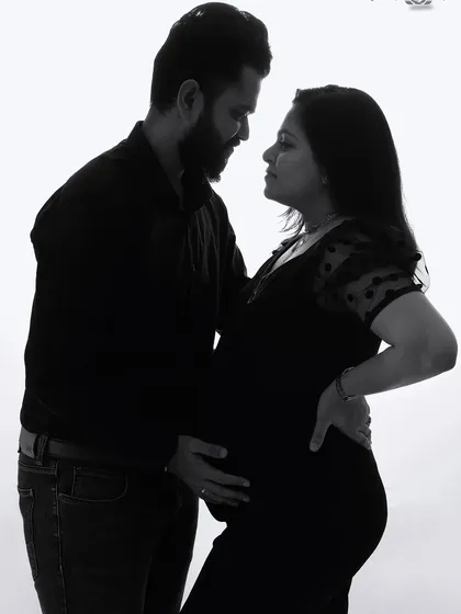 A classic black and white portrait of an expecting couple. This high-key photo creates a timeless and elegant look, focusing on their connection and the silhouette of the pregnancy.