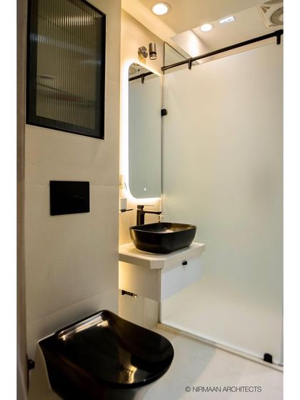 This sleek master bathroom features a black wall-mounted toilet and a frosted glass partition for the shower area. The design is minimalist, modern, and easy to maintain.