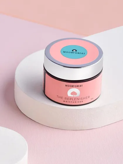 A clean, geometric composition of Moon Forest's "The Replenisher" moisturizer. The use of layered platforms and a pastel color palette gives it a soft, contemporary look.