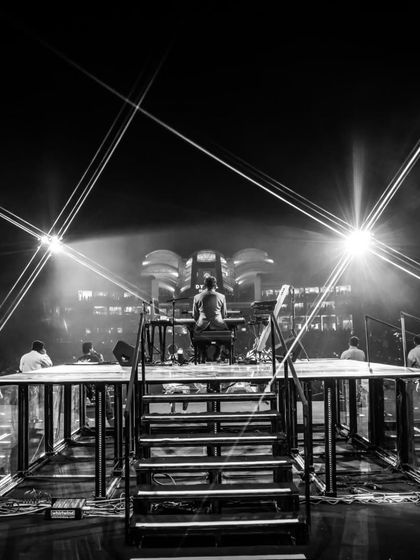 A view from the stage during soundcheck for 'The Wonderment Tour'. This black and white shot highlights the intricate lighting rig and stage structure before the audience arrives, showing the calm before the storm.