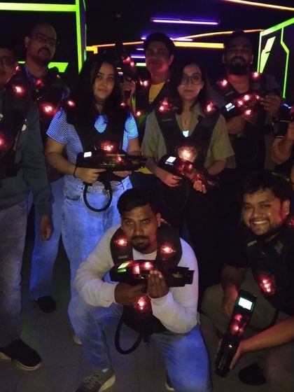 A group of friends is ready for their laser tag mission. The glowing red lights on their vests indicate they are in the middle of an intense game.