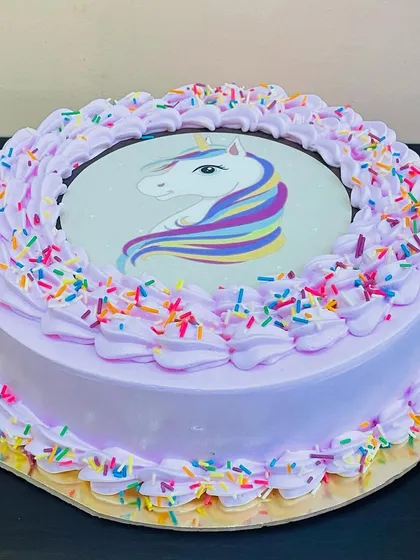 A magical unicorn cake with a beautiful edible print, surrounded by rainbow sprinkles. This design is a whimsical and popular choice for birthday celebrations.