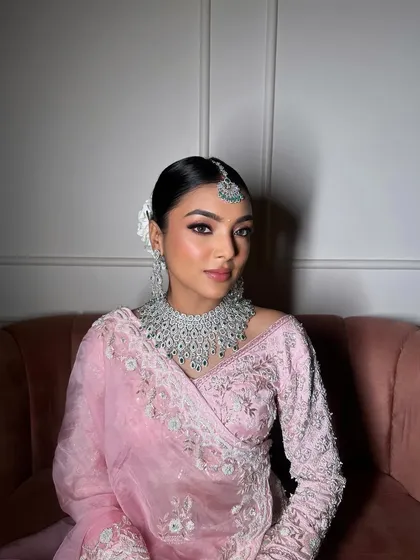 The client looking flawless in pastel pink. The sleek bun and fresh flowers complement her diamond and emerald jewelry perfectly.