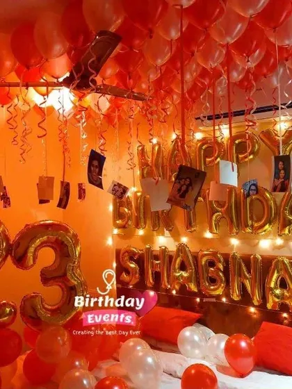 A vibrant and personalized 23rd birthday room decoration. The setup includes a ceiling full of red and white balloons, foil number balloons for the age, and the birthday girl's name spelled out in gold letters.