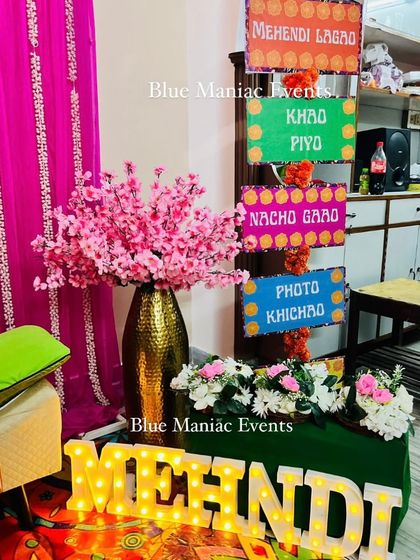 Details from our vibrant Mehendi setup, including 'MEHNDI' marquee letters and a stand with fun, directive signs for guests.