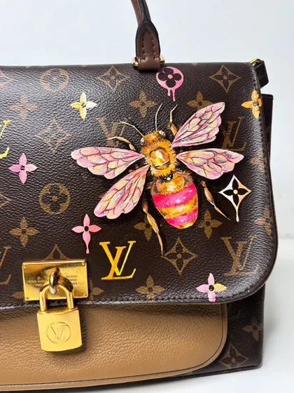 A close-up of the finished, colorful bee on the LV bag. The pink wings and vibrant details really pop against the classic monogram.