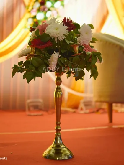 A floral arrangement on a tall, slender brass stand. This type of decor element can be used to line aisles or add visual interest to corners of a room without taking up table space.