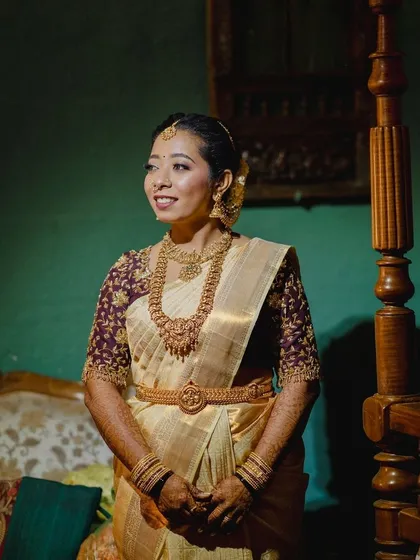 A beautiful indoor portrait of the bride. The warm lighting enhances the golden tones in her saree and jewelry, and her makeup is glowing and flawless.