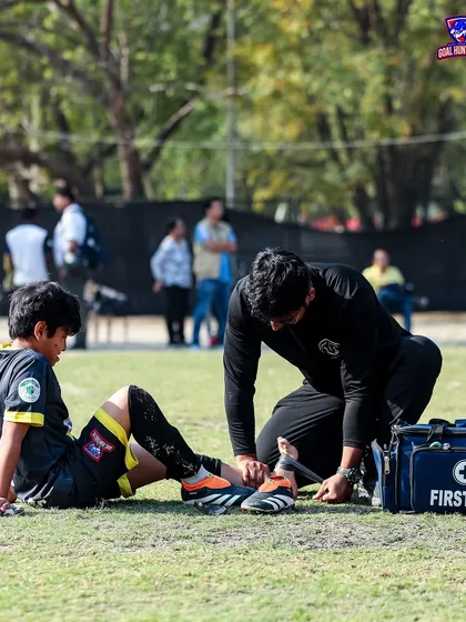 Our first aid team helping a young player with his boots, ensuring they are safe and ready to play.