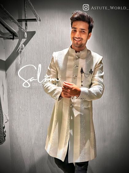 A client looking happy and confident in a striped off-white Indo-Western sherwani. The asymmetrical cut and sharp tailoring give this traditional garment a modern edge.
