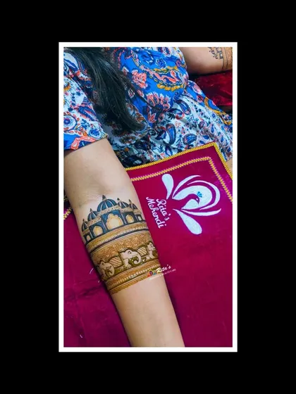 An arm band featuring an architectural dome and a line of elephants, part of a larger bridal design.