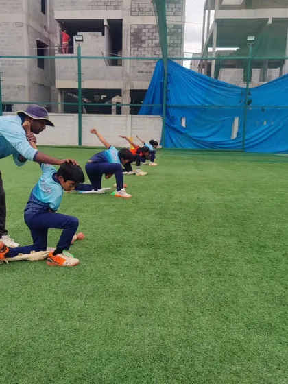 A coach correcting a player's posture during a bowling drill. This hands-on approach is consistent across all our branches.