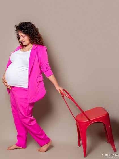 Another creative use of the red chair prop. This walking pose adds a sense of movement and style to the modern studio portrait.