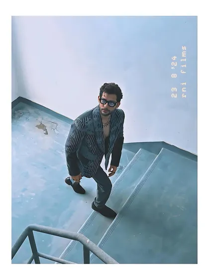 Mohit Hiranandani wears the grey velvet coat in a more artistic, moody setting. The high-angle shot gives a unique perspective on the jacket's structure and detailed embroidery.