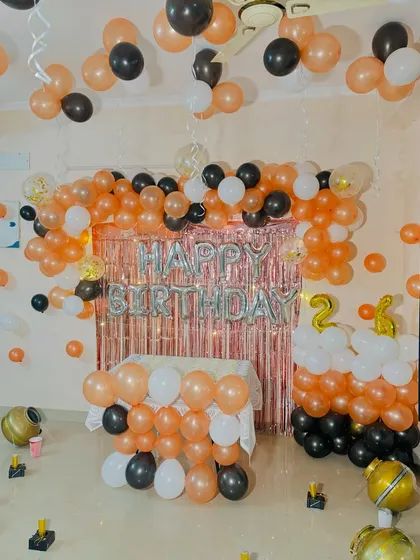 A full room decoration for a 21st birthday, with a balloon arch, tinsel curtain, and balloons on the ceiling.