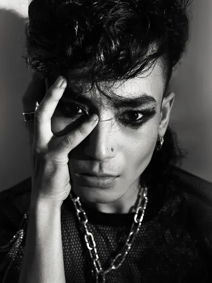 An expressive, emotional close-up. The model's hand covering his eye and his intense gaze create a powerful, vulnerable, and raw portrait.