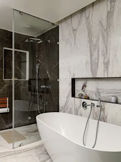This modern bathroom is a masterpiece of architectural ingenuity. The contrast between the dark and light marble, the freestanding tub, and the glass-enclosed shower creates a sense of luxury and royal sophistication.