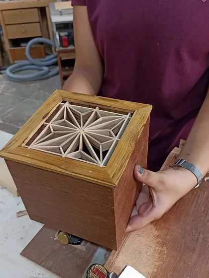 A 16-year-old student holding the Kumiko box she just completed. The lid features a stunning Asa-no-ha pattern, a complex design she mastered over the course of the workshop.