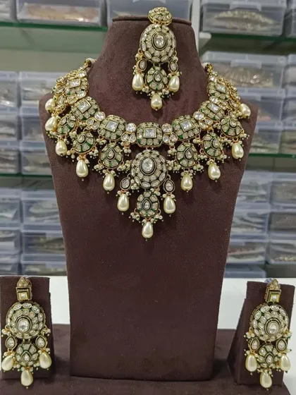 A beautiful Polki and Kundan choker set with matching earrings and maang tikka. The mint green stones and pearl drops give it a fresh, modern feel, perfect for a day wedding.