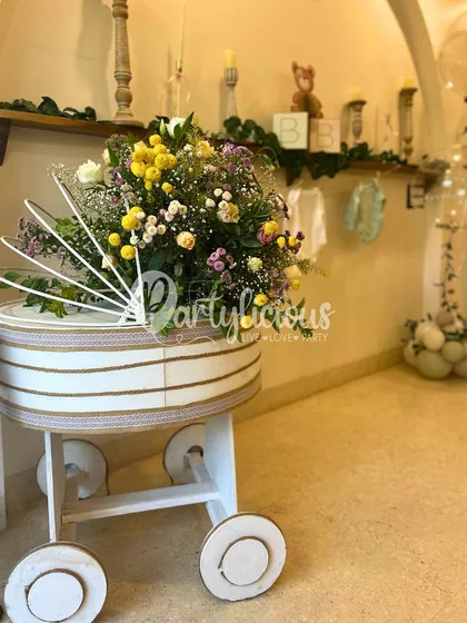 A vintage-style pram filled with a beautiful arrangement of wildflowers, serving as a stunning and unique prop for a baby shower.