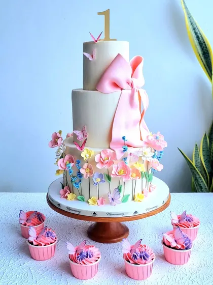 The floral first birthday cake with matching pink and purple cupcakes.