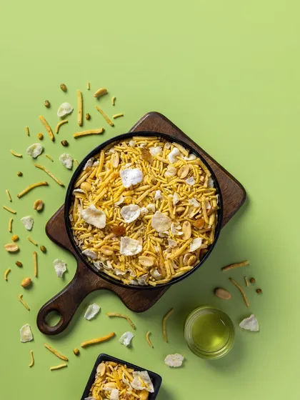 A classic Khatta Meetha mixture photographed for Sartaj Sweets' packaging line. The light green background gives the image a fresh and inviting feel.