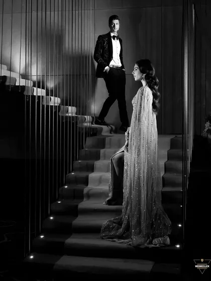 A dramatic black and white portrait of the couple on a staircase. The contrast and composition give this image a classic, cinematic feel.