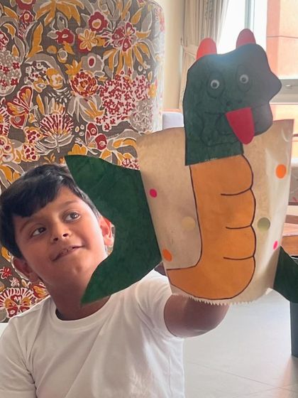 A young boy holds up his completed dragon puppet. The sense of achievement they feel is just wonderful to witness.