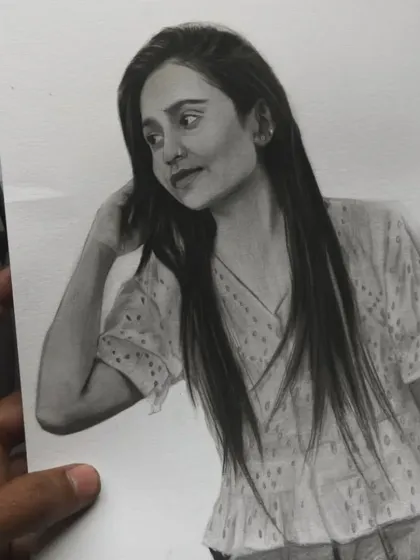 Holding up the finished portrait to compare it with the original reference on the phone.