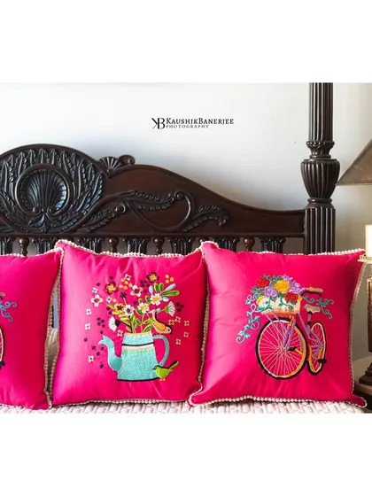 This setup features a vibrant pink cushion set with bicycle and floral motifs. Placing them in a series like this helps customers visualize the entire collection and see how different designs coordinate.