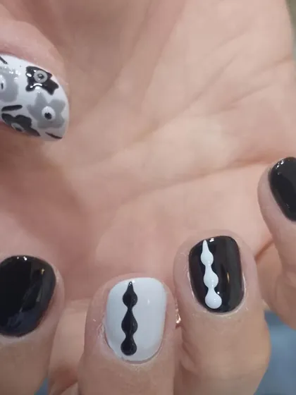 A minimalist black and white design with abstract lines and a simple floral accent nail.