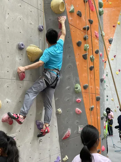 A climber navigates a route while others watch from below. The community aspect of sharing beta and encouragement is a huge part of the fun.