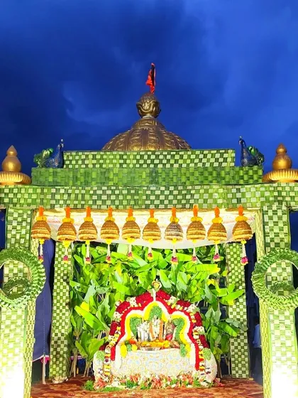 A beautiful outdoor deity setup against a dramatic night sky. The *chappara* is made of woven leaves and features a temple dome.