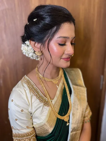 A serene portrait of the bride. Her eyes are closed, showing off the soft, shimmery eyeshadow that complements her traditional attire.